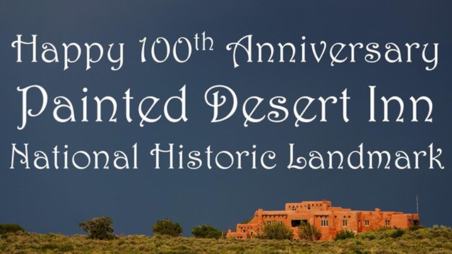 White font on dark sky over green shrubs and pueblo style building