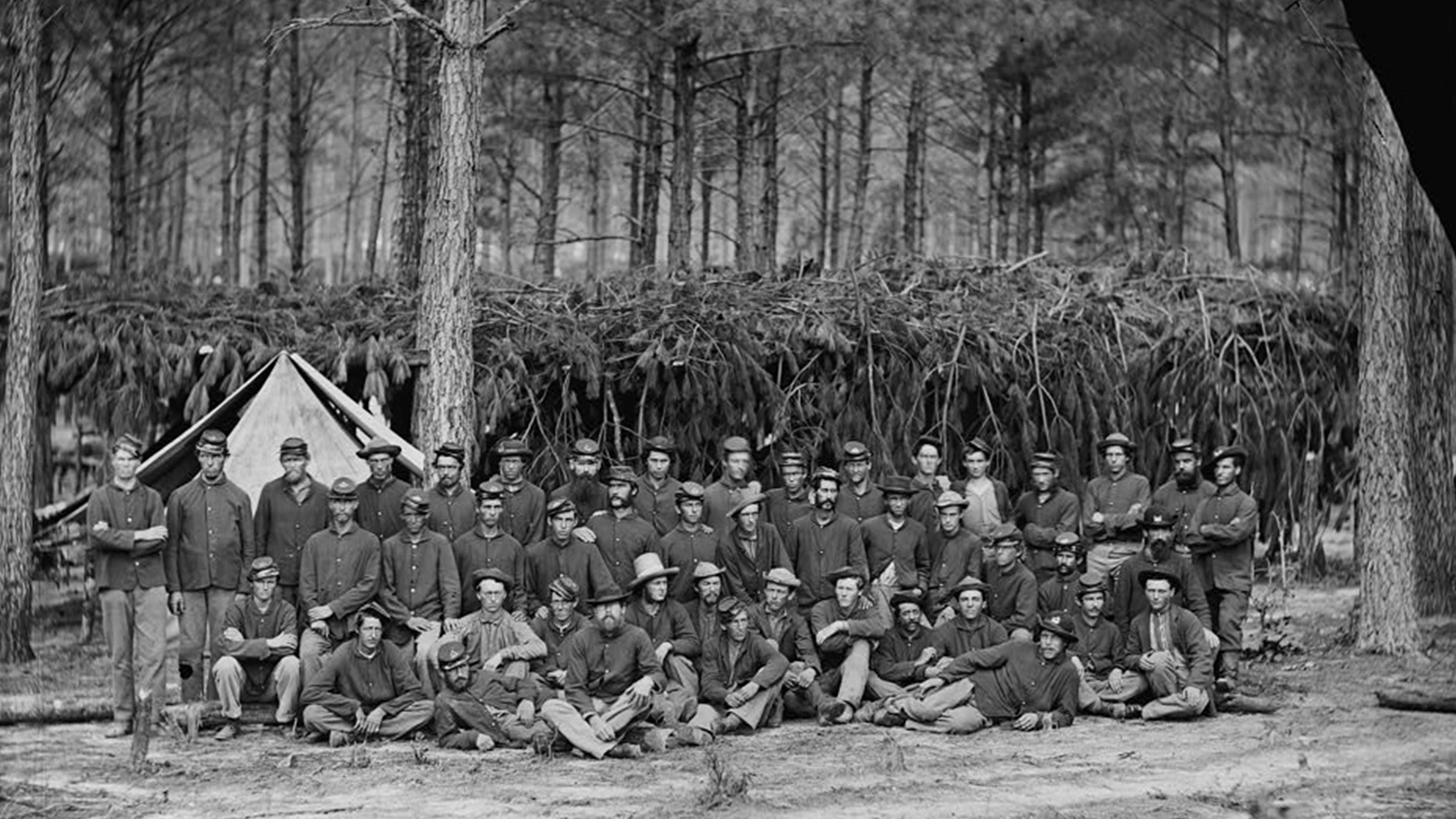 Group photo of 45 men in 3 rows all wearing US Civil War uniforms. 