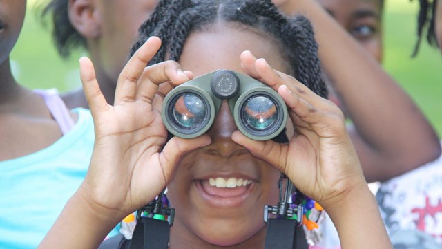 A small child looking through binoculars