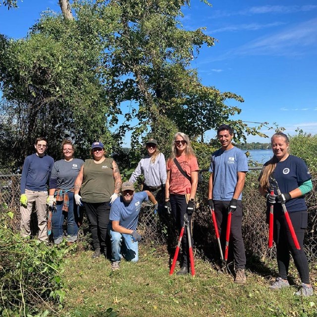 A group of volunteers standing outside in front of a tree.