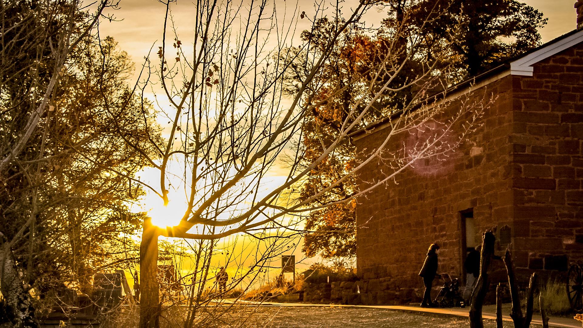A sandstone fort backlit by the sunset. Golden sunrays behind the building.