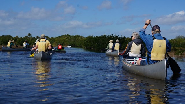 Girl in kayak on tree-lined river