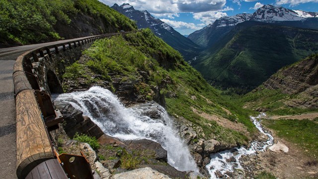 Waterfall cascading next to mountain road on sunny day