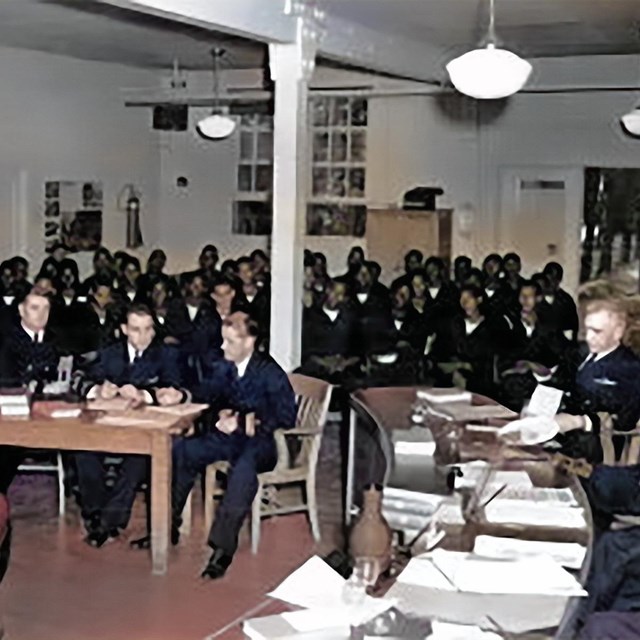Photograph depicts a crowded courtroom scene with naval officers and sailors.
