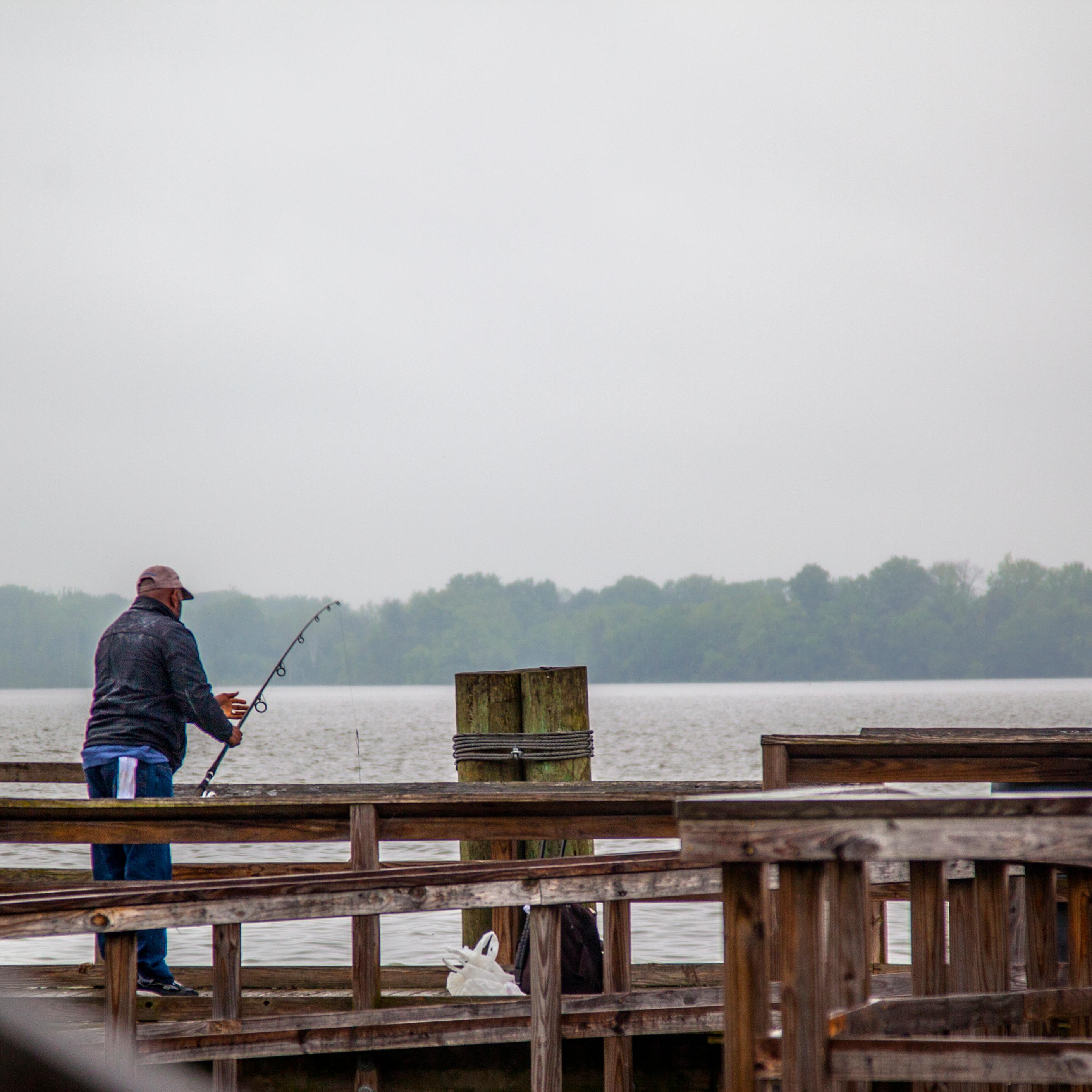 A person fishing on a pier by the water