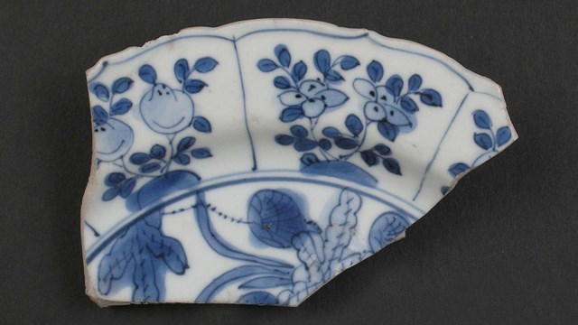 A shard of Chinese white porcelain plate decorated with blue fruits and flowers.