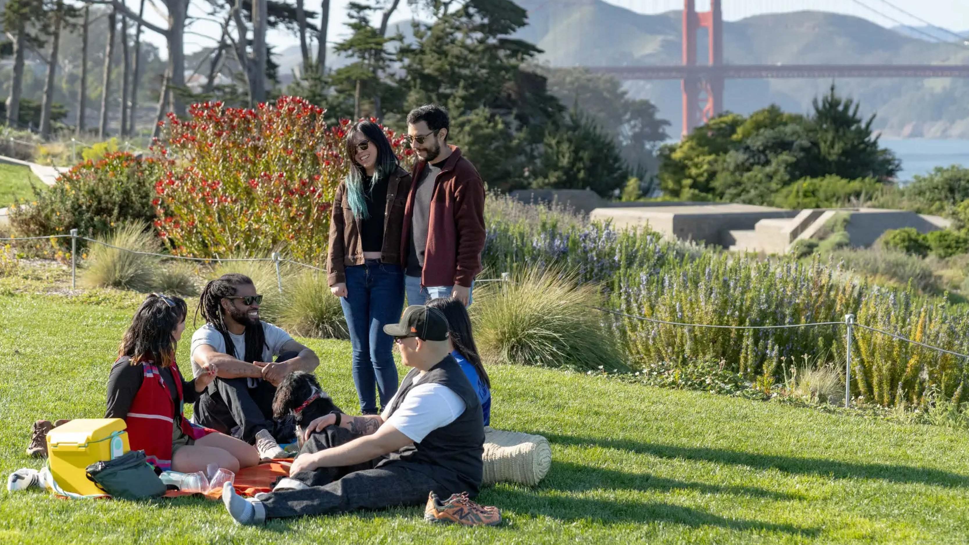 Image showing a group of people laughing at a picnic with Golden Gate Bridge in the background.