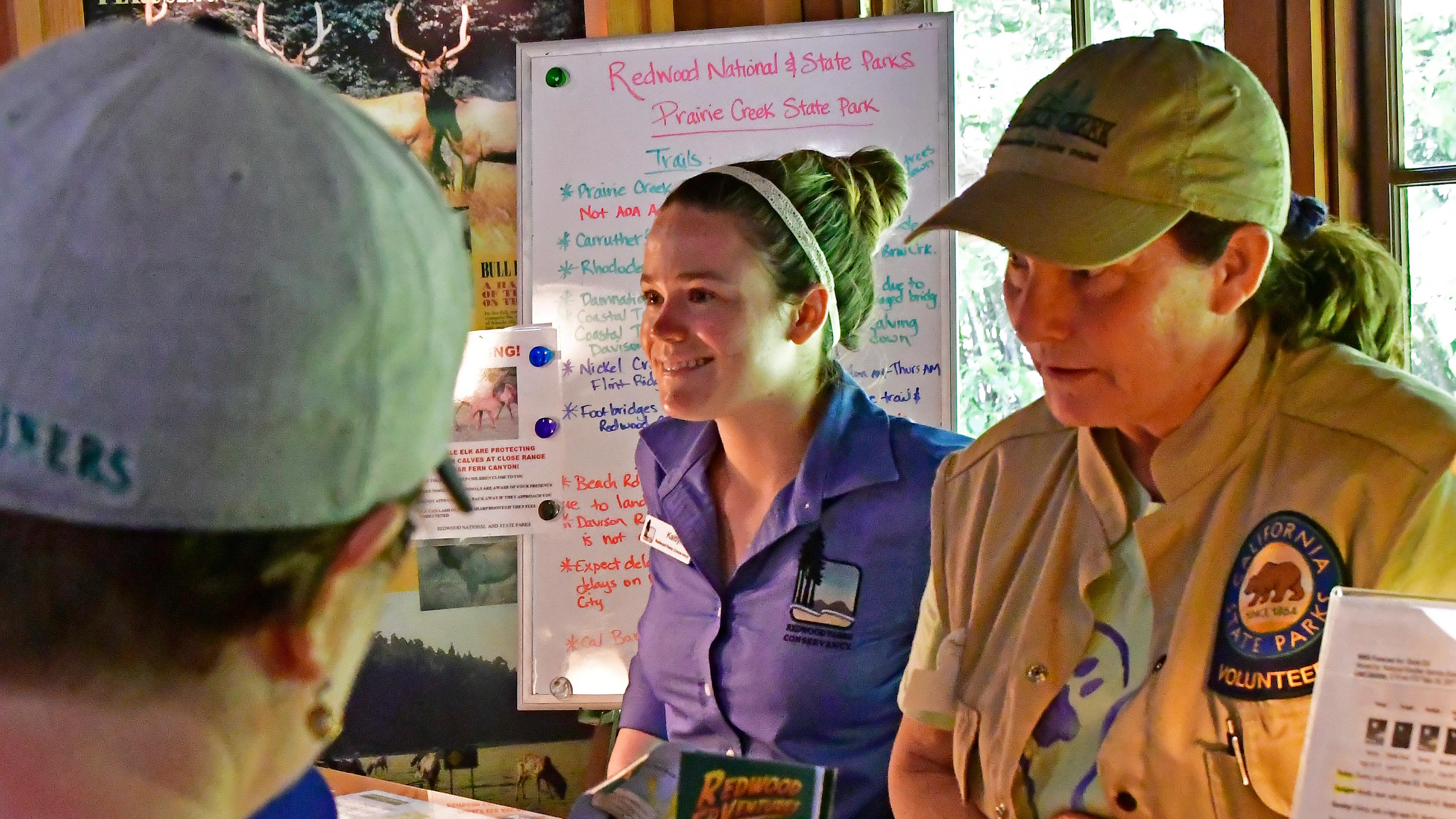 An image of a young and adult woman at a visitor center desk. 
