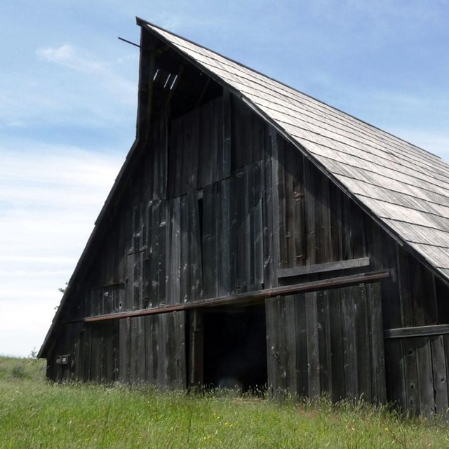 A large wood barn with a high peak roof