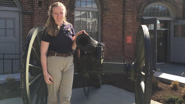 An intern posing in front of a cannon.