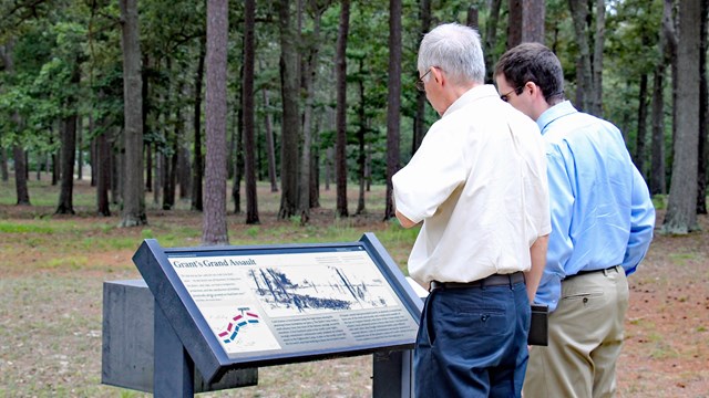 Two visitors examine an outdoor wayside sign.