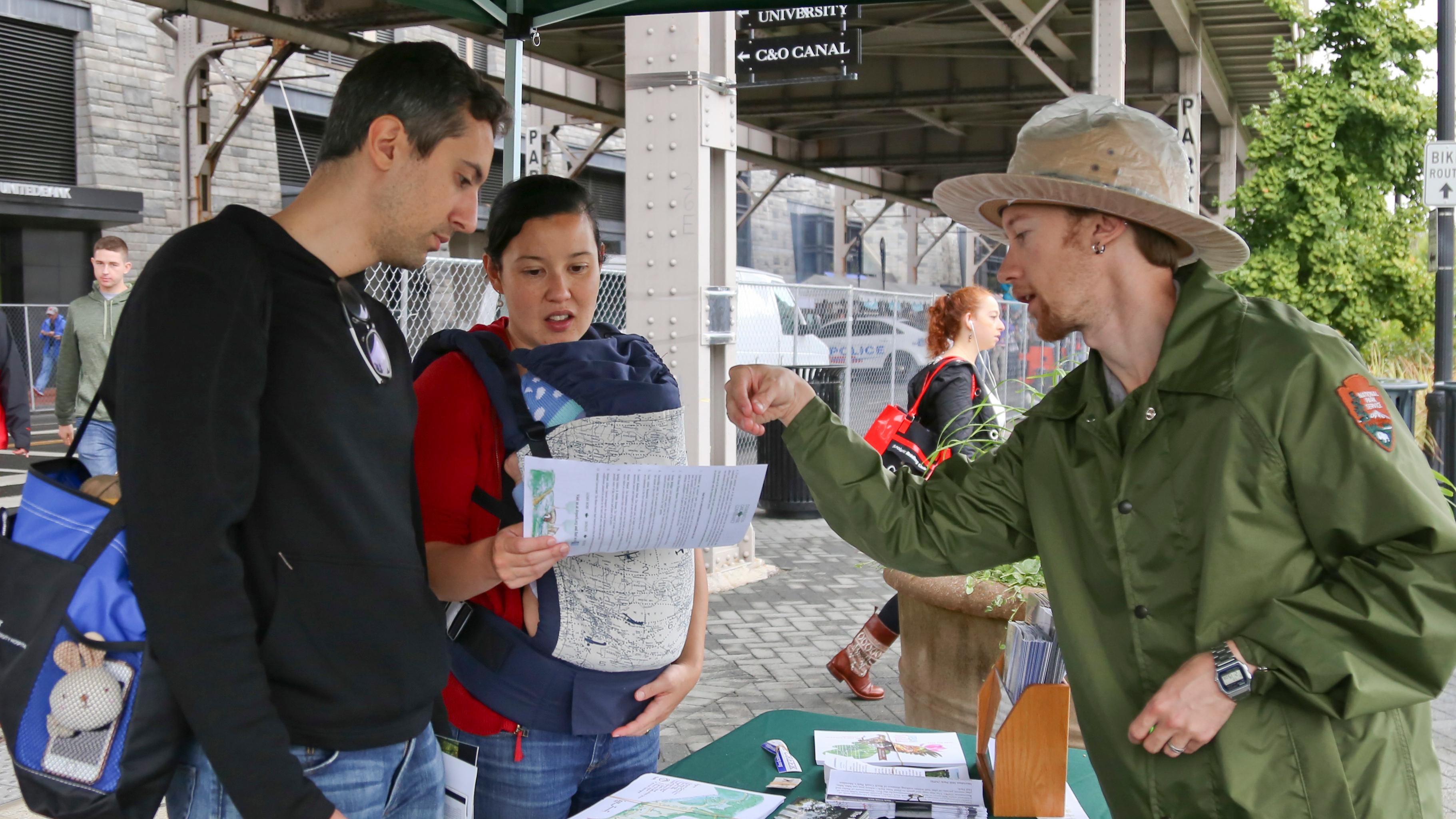 A ranger talks to visitors under a tent during an event
