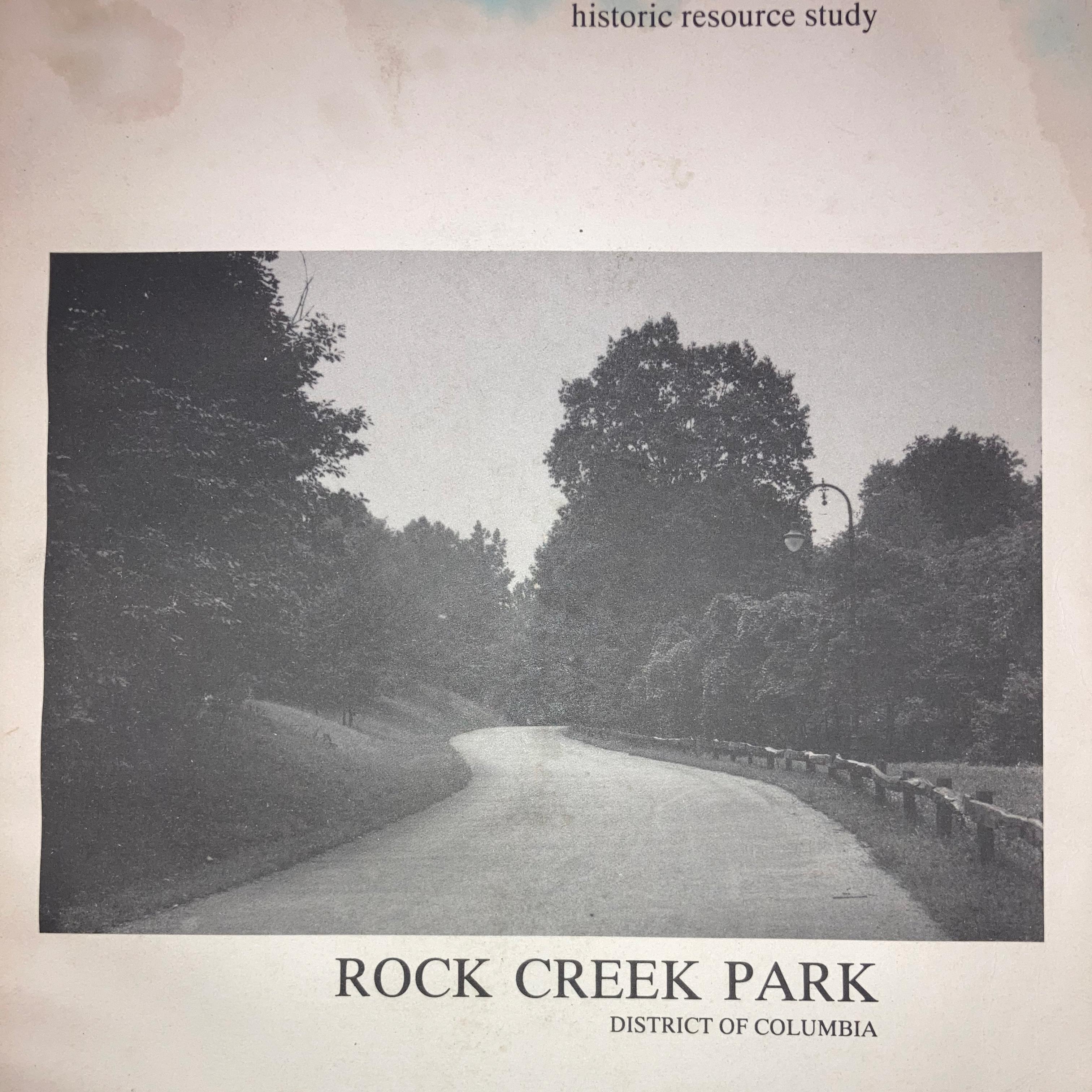 black and white image of a road disappearing into trees