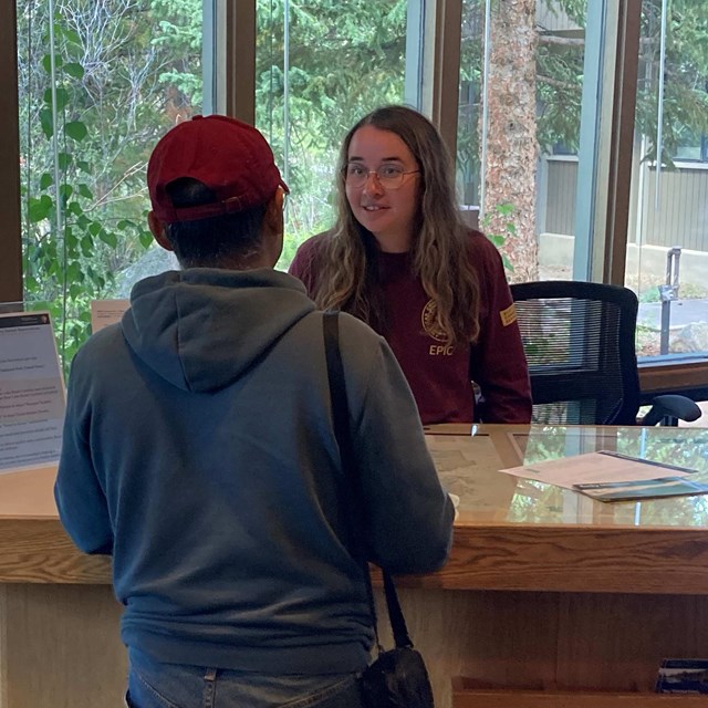 A park intern is helping visitor at the Kawuneeche Visitor Center plan their trip