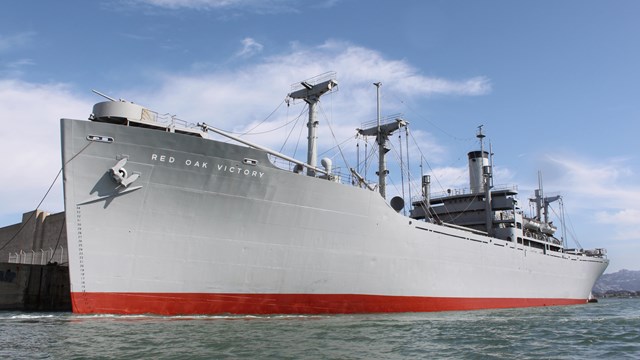 Photo of the SS Red Oak Victory Ship from the side as it's docked in the bay.