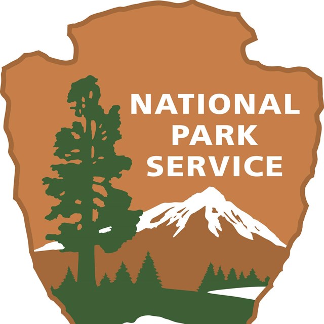 Official NPS shield logo showing illustration of mountains, trees, and a buffalo. 