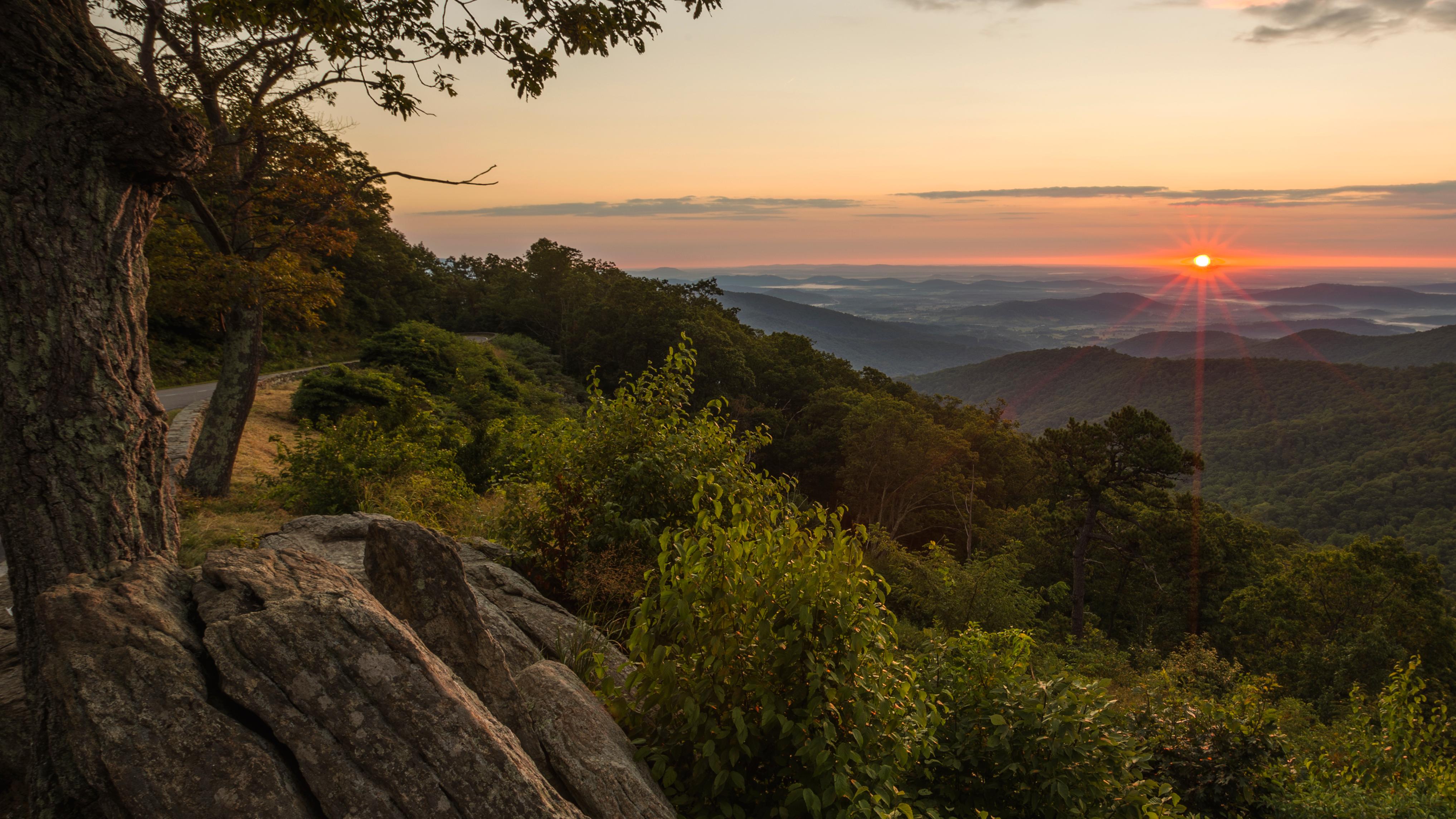 A sunset over a forest mountain scene