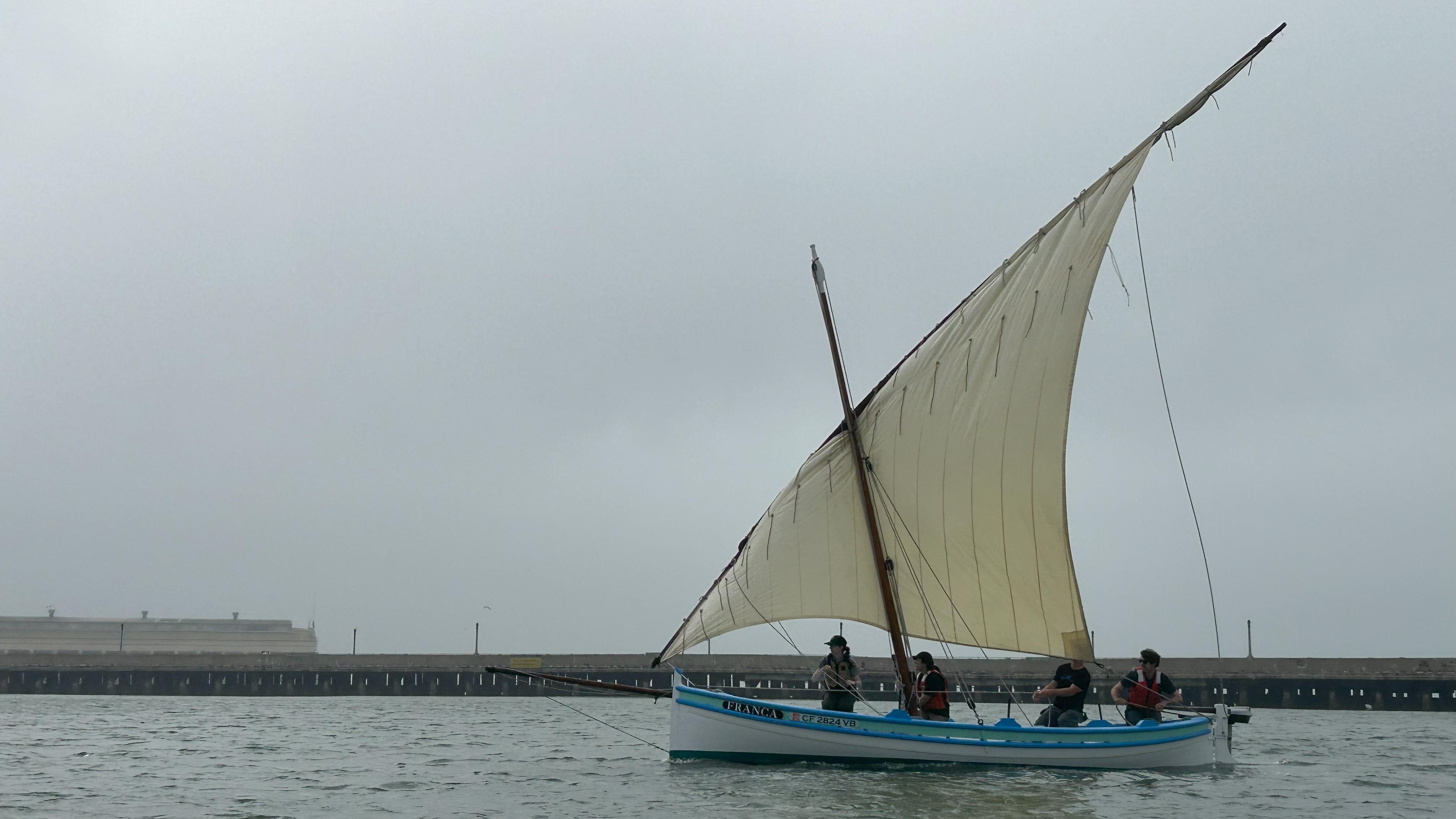 people pull lines on a sailboat in Aquatic Cove with misty weather around them