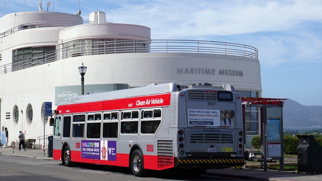 A SF city bus stops in front of the Maritime Museum