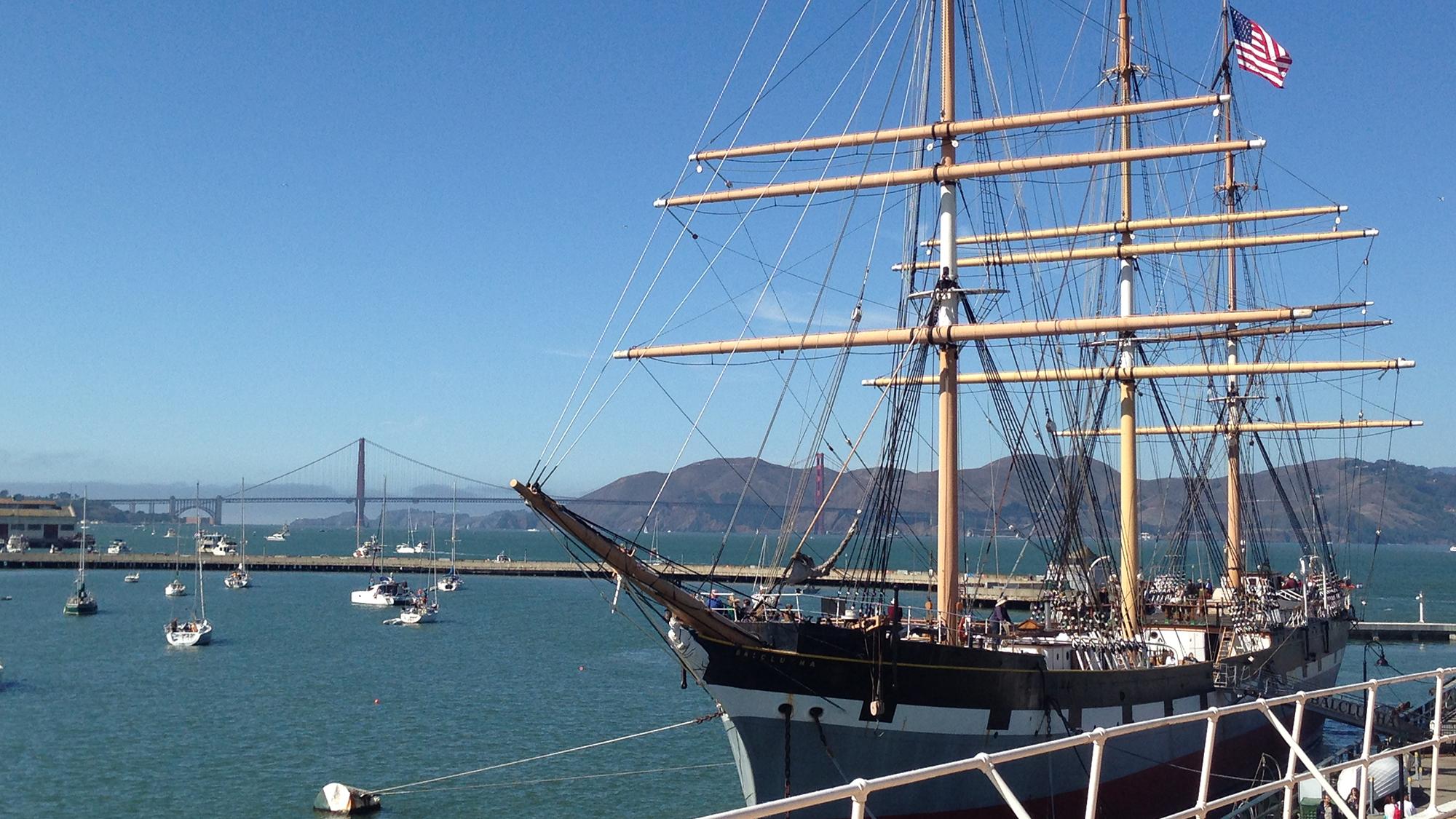 A restored historic sailing ship built in 1886 moored along a pier.