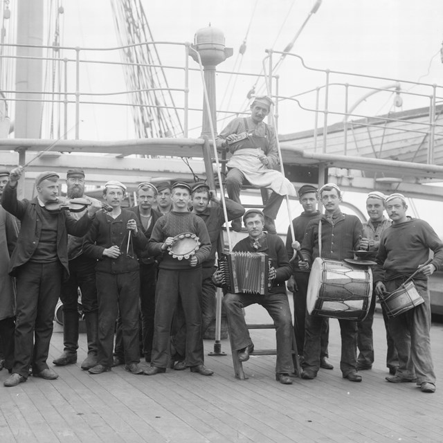 historical photograph of men with instruments standing on the deck of a ship