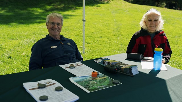 two volunteers seated at an outdoor information table