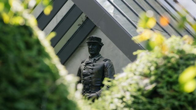 bronze sculpture between green hedges