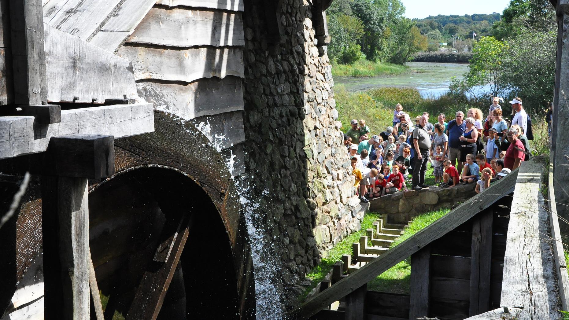 group of visitors watching a waterwheel turn