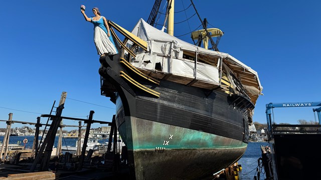 A large wooden ship getting repair work performed.