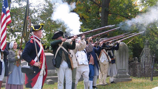 Revolutionary War costumed interpreters fire their muskets