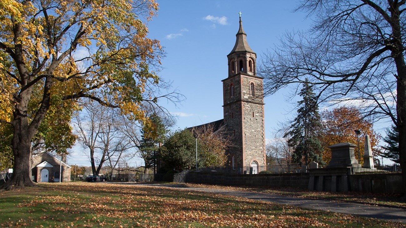 Stone and brick church, trees without leaves, lawn with green grass 
