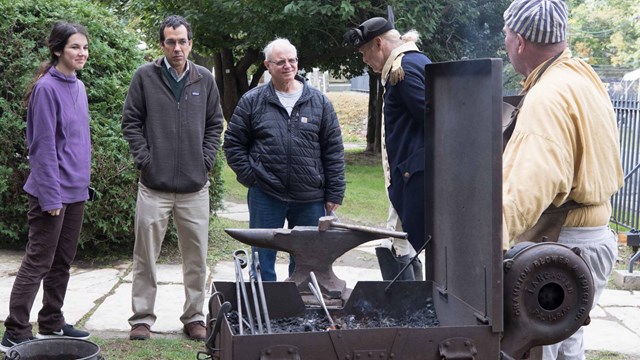 Colonial crafts re-enactor with contemporary visitors.   