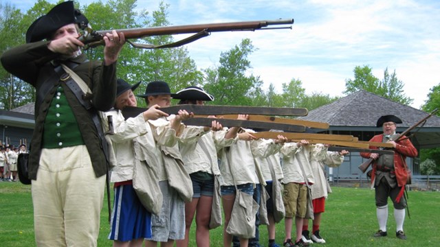 An 18th century soldier conducting musket drill with a group of students