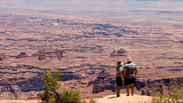 A couple stands at the edge of a canyon