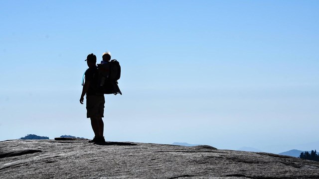 A hiker carries a tot in a backpack. Photo by Katie Kenig.