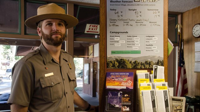 A ranger in uniform and flat hat stands at the information desk in the Kings Canyon Visitor Center.