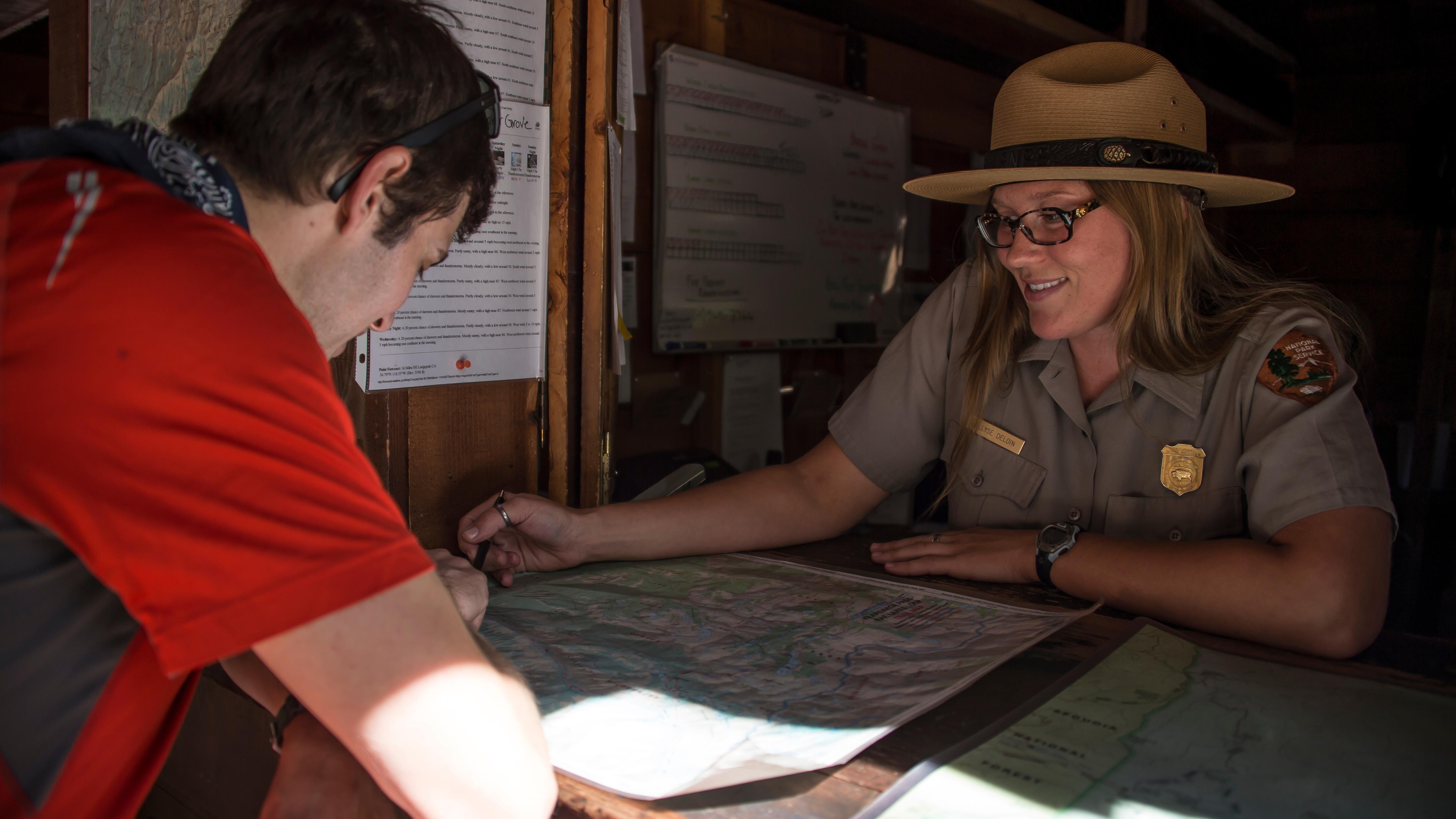 A ranger at a desk talks with a person. Photo by Alison Taggart-Barone.