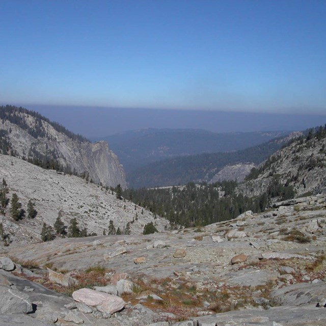 A distant hazy sky with particulate matter forms over Sierra mountains.