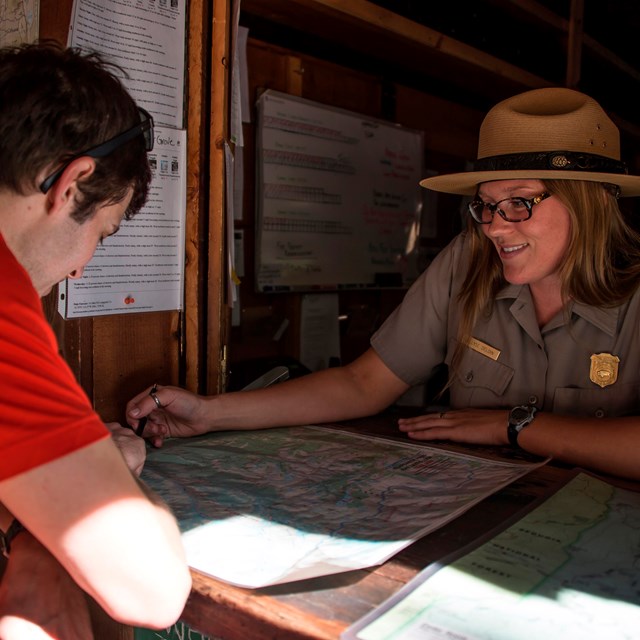 A ranger at a desk talks with a person. Photo by Alison Taggart-Barone.