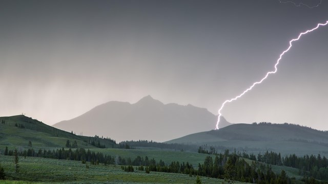 Lightning strikes Electric Peak as a dark storm rolls over the mountain.