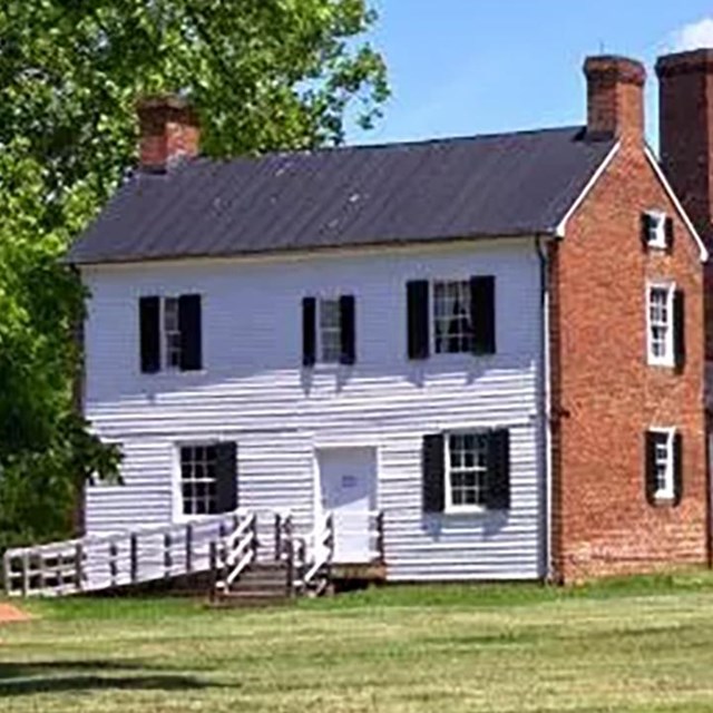 a mansion sitting in an open field with trees and a blue sky