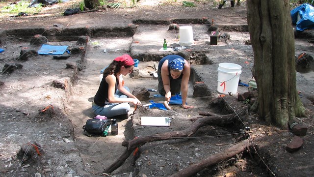 students in perfectly dug rectangular holes at a dig site 