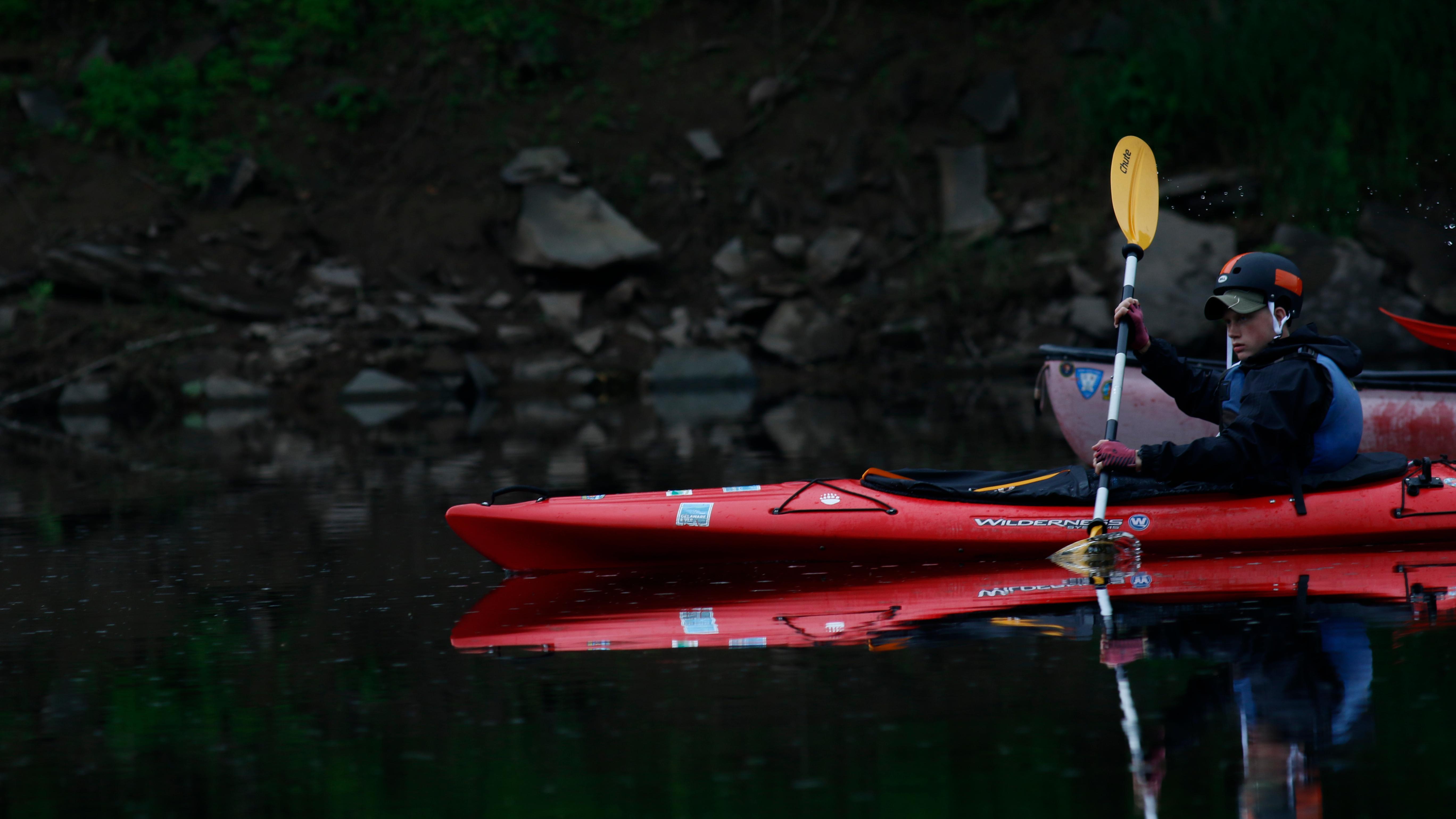 Young boy in kayak cuts through the water.