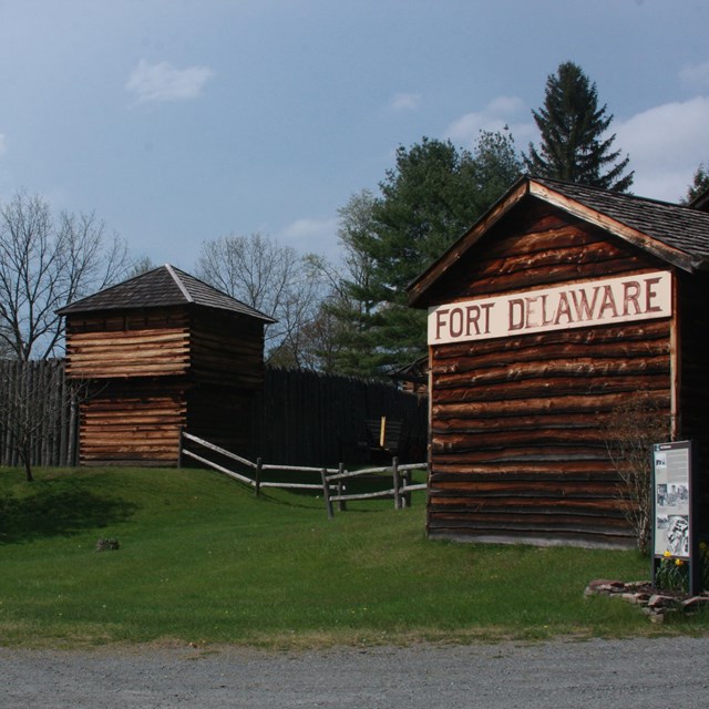Wooden buildings with rail split fence. One building has sign with painted text 