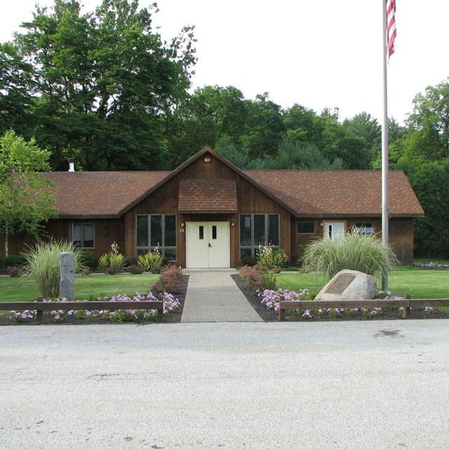 1-story brown building with American flag and landscaping