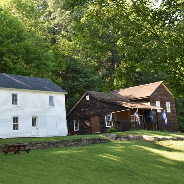 White 2-story house next to brown wood plank house