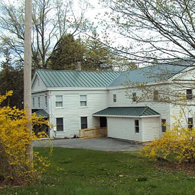 Two story white house with pale green roof