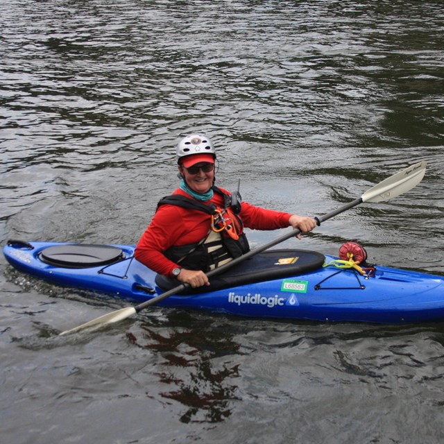 Volunteer in blue kayak on the water