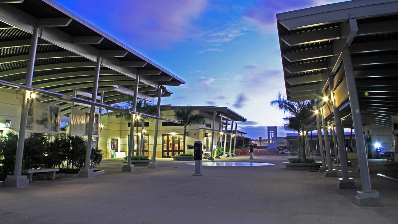 A photograph of a pathway between the visitor center building at dusk. 