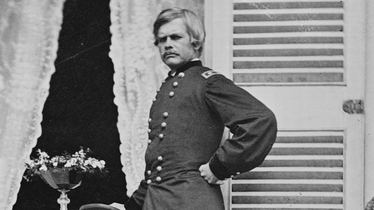 A black and white image of Edward Ord standing with his hand on a table, chair to his backside.